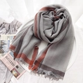 Lightweight grey wool scarf with brown stripes and tassels on a minimalist white table - Grey Striped Style