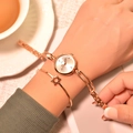 Elegant rose gold watch and star bracelet set displayed on a woman wrist in a warm cafe - White Dial