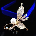 Elegante spilla a foglia d'oro con perla bianca e cristalli scintillanti su fondo nero - Perla di narciso