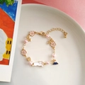 Detailed shot of cat and Mount Fuji charms on a pink cherry blossom pearl bracelet - White
