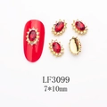 Macro shot of 7x10mm K9 red crystal nail gems with gold alloy and white diamond rhinestones - 3099 Bright Red Gold Base Oval (LF3099)