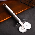 Dual stainless steel pizza cutter wheel with smooth and wavy blades on dark stone surface - Double Wheel Pizza Cutter