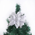 Nahaufnahme einer silbernen Glitzer-Weihnachtsblume an einem grünen Tannenzweig - Silber
