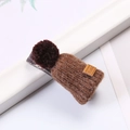 Close-up of a brown handmade plush hat hair clip on a white card with green leaves - Brown