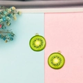 Macro detail of two kiwi fruit slice charms with gold metal edges for DIY jewelry - Kiwi