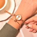 Rose gold quartz watch and star bracelet set on woman's wrist in warm lighting - Gold Dial