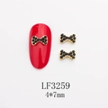 Macro de bijoux d'ongles nœud doré 4x7mm avec strass noirs sur une manucure rouge - Base Dorée Strass Noir (LF3259)