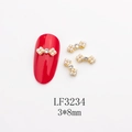 Macro view of 3x8mm alloy bow nail charm with pearl and rhinestone on a red nail - Gold Base Pearl White Rhinestone (LF3234) / 3*8mm