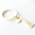 Close-up of cream leather keychain bracelet with tassel and round metal engraving tag - Off White