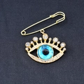 Detailansicht der Evil Eye Brosche mit blauen Steinen und Kristallen auf goldener Nadel - Gold