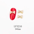 Vue macro de bijoux d'ongles nœud 9x6mm avec perles et strass sur un ongle rouge - Nœud Doré Pavé de Perles et Strass Blancs (LF3216)