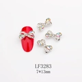 Dettaglio di ciondoli per unghie a fiocco argento con cristalli AB 7x13mm su unghie rosse - Stile Strass Bianco AB Base Argentata (3283)