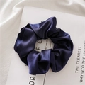Dettaglio di elegante elastico per capelli in raso blu navy con trama setosa su rivista - Blu navy