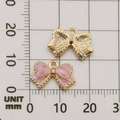 Pink and gold bow-shaped alloy pendants displayed on a grid for size measurement - Pink Bow Tie