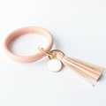 Close-up of pink leather bangle keychain with tassel, gold hardware and round charm - Pink