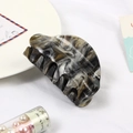 Detail of marble pattern acetate hair claw clip with anti-slip teeth on white plate - Starry Black Marble