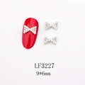 Détail d'ongle rouge avec breloque nœud en perle blanche et base en métal argent - Petit Nœud Argenté avec Perle et Strass (LF3227)
