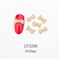 Dettaglio macro di ciondoli per unghie a fiocco dorati 5x10mm con strass su unghie rosse - Stile Strass Trasparente Pavé Base Dorata (3288)
