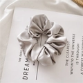 Silver-gray satin hair scrunchie with silk texture shown on a magazine page - Gray