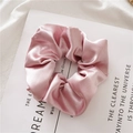 Elegant pink satin crystal scrunchie with soft pleated texture on a magazine background - Pink