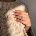 Luxurious square-cut zircon halo ring with side diamond accents on female hand - US 8 / White