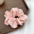 Elegant pink satin scrunchie displayed on a rustic wooden tray with a silk texture finish - Pink