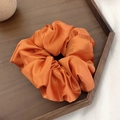 Chouchou géant en satin orange élégant avec un fini brillant soyeux sur plateau - Orange