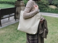 Detail of a large canvas tote bag with leather handles in a natural outdoor park setting - Khaki
