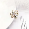 Elegante spilla a fiore dorata con strass bianchi e perle dal raffinato design floreale - Fiocco in Zirconia