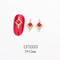 Vue macro de bijoux d'ongles en forme de croix avec pierre rouge et petits diamants blancs - Style Croix Diamant Rouge Base Or (LF3333)