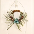 Christmas wreath with blue bells, pine cones and frosted pine needles on a white door - Three Bells - Blue