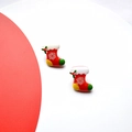 Detail shot of Christmas stocking earrings with white snowflake and holly leaf patterns - Red Boots