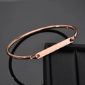 Gros plan du bracelet jonc doré rose en forme de C avec plaque métallique rectangulaire polie - Or rose