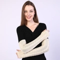 Primer plano de calentadores de punto crema con trenzado en los brazos de una modelo - Talla única / Beige
