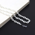 Close-up of a white acrylic glasses chain with silver clips on a white book surface - White