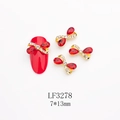 Detail showing red alloy bow nail art charm with K9 crystals on a red manicured nail - Gold Base Red Rhinestone Style (3278) / 7*13mm