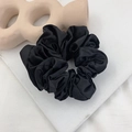 Elegant large black satin scrunchie hair tie with soft pleats on a minimalist background - Black