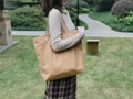 Outdoor shot of a khaki canvas tote bag with leather straps and reinforced rivets - Camel