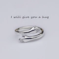 Detalle macro de anillo de manos de abrazo en plata con un diseño abierto ajustable - Ajustable / Plateado