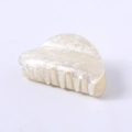 Detailed macro view of pearly white acetate claw clip with marble texture and grip teeth - Champagne Water Ripple Round Head
