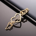 Macro shot of gold metallic heart hair clip with angel wings on black reflective surface - Gold Cupid Heart Hairclip