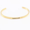 Détail du bracelet mantra en acier doré avec gravure Survivor sur la surface - SURVIVANT