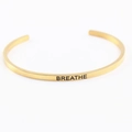 Golden stainless steel cuff bracelet featuring a minimalist BREATHE engraving design - BREATHE