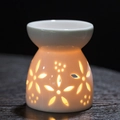 White ceramic essential oil burner with hollow floral patterns and warm light glow - Quisqualis / Aromatherapy Burner + Candle Tray