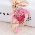 Golden goldfish keychain featuring pink crystals and enamel detail on white plush background - Pink Lucky Fish