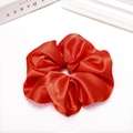 Detail shot of a bright red satin scrunchie with shiny pleated texture on white background - Red