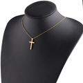 Dettaglio di un ciondolo a croce minimalista in acciaio dorato su un modello da collo - Croce 15x30mm / Oro