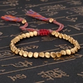 Pulsera étnica artesanal con cuentas doradas irregulares y cordones de borlas de colores - Estilo Brillante
