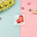 Close-up of a red heart-shaped resin charm in a transparent candy bag packaging - Red Heart