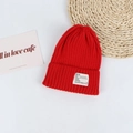 Detail of red ribbed knit beanie featuring a white rectangular patch with decorative text - Head Circumference 50-58cm / Red